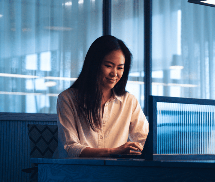 professional services employee smiling and writing on her laptop